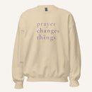cream sweatshirt with 'Prayer Changes Things' purple text on a cream background