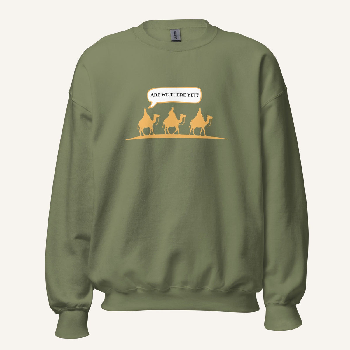Green unisex crewneck sweatshirt featuring a gold desert scene with three camels and a speech bubble reading “Are we there yet?”