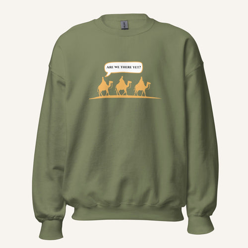 Green unisex crewneck sweatshirt featuring a gold desert scene with three camels and a speech bubble reading “Are we there yet?”
