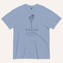 A muted blue short-sleeve crewneck t-shirt with a black line-art mustard seed graphic and the text 'FAITH as small as a mustard seed' and 'MATTHEW 17:20' printed on the front, displayed against a light cream background.