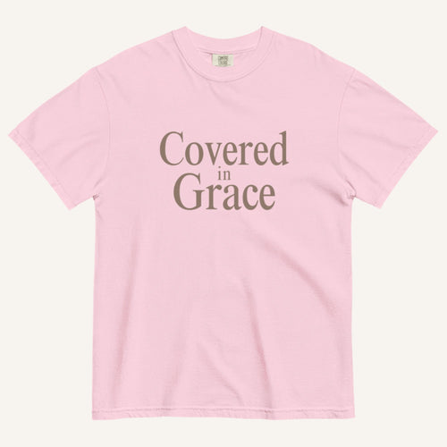 Pink t-shirt with 'Covered in Grace' text on a white background