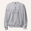 A light heather gray crewneck sweatshirt featuring a black graphic of a cross on a hill with the word 'Redeemed' printed below it, displayed on a clean off-white background.