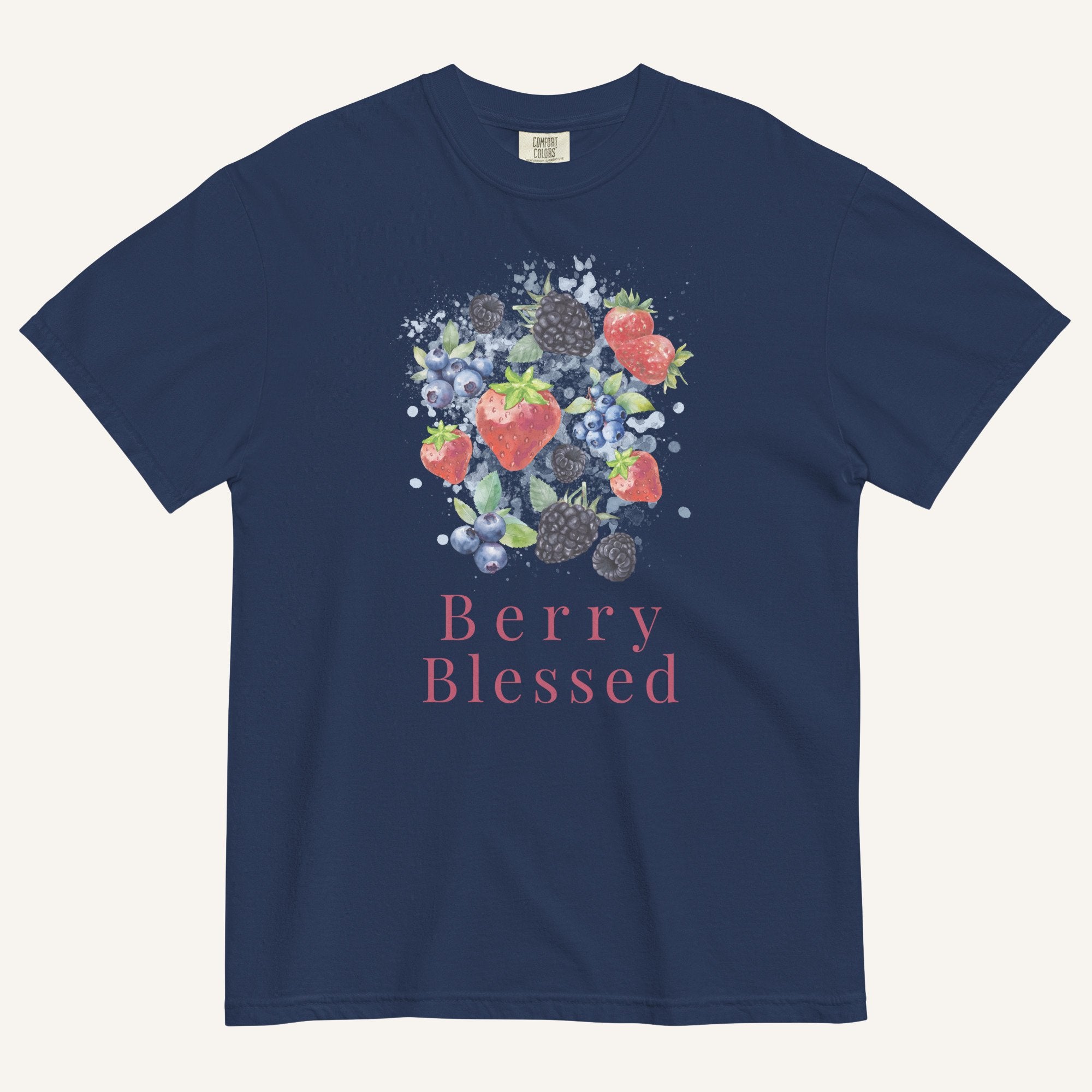 A navy blue short-sleeve t-shirt with a watercolor-style graphic of various berries (strawberries, blueberries, blackberries) and the text 'Berry Blessed' printed below it in pink, displayed on a light cream background.