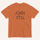 An orange short-sleeve crewneck t-shirt with 'JOHN 3 16' text with cross graphic in between the 3 & 16 printed in a black hand-drawn font on the chest, displayed flat against a light cream background.
