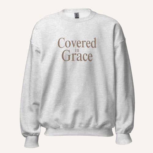 light grey sweatshirt with 'Covered in Grace' text on a cream background