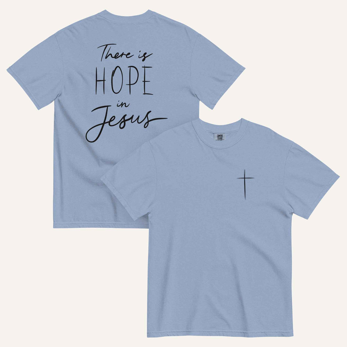 A muted dusty blue t-shirt shown from both the front and back. The front features a small black cross on the top left. The back features the black text 'There is HOPE in Jesus' in a mix of script and block lettering.