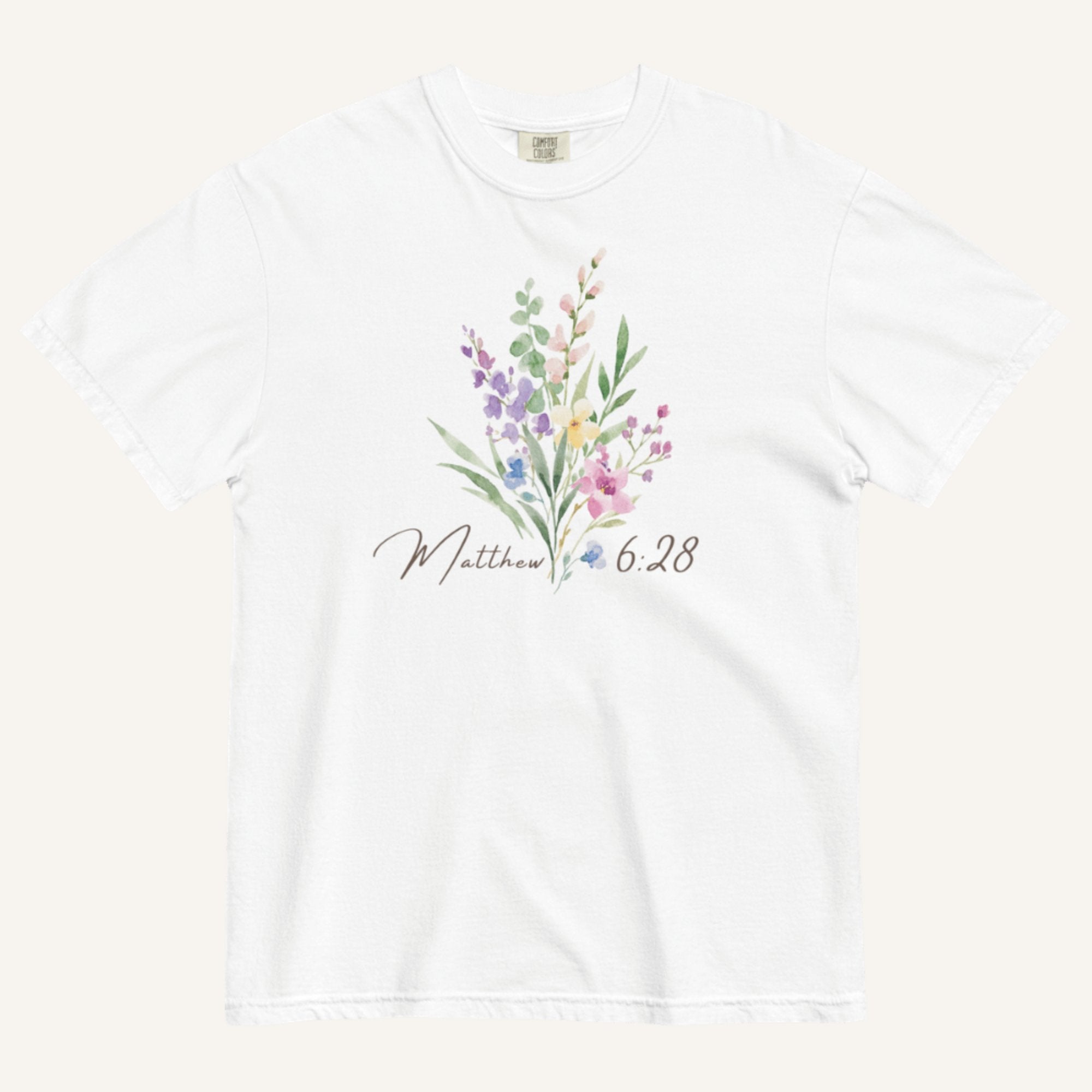 White t-shirt with floral design and 'Matthew 6:28' text on a white background