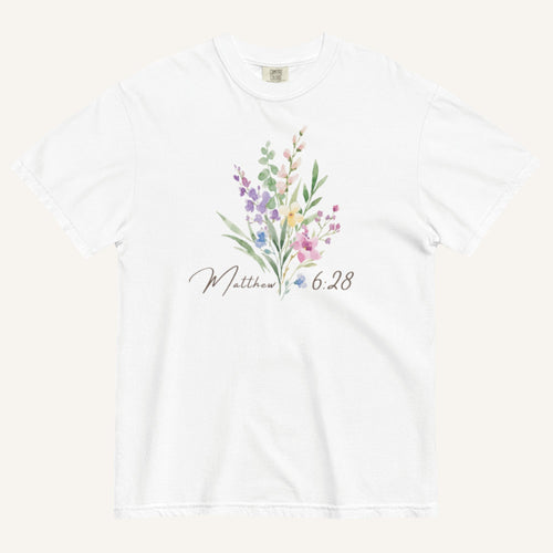 White t-shirt with floral design and 'Matthew 6:28' text on a white background