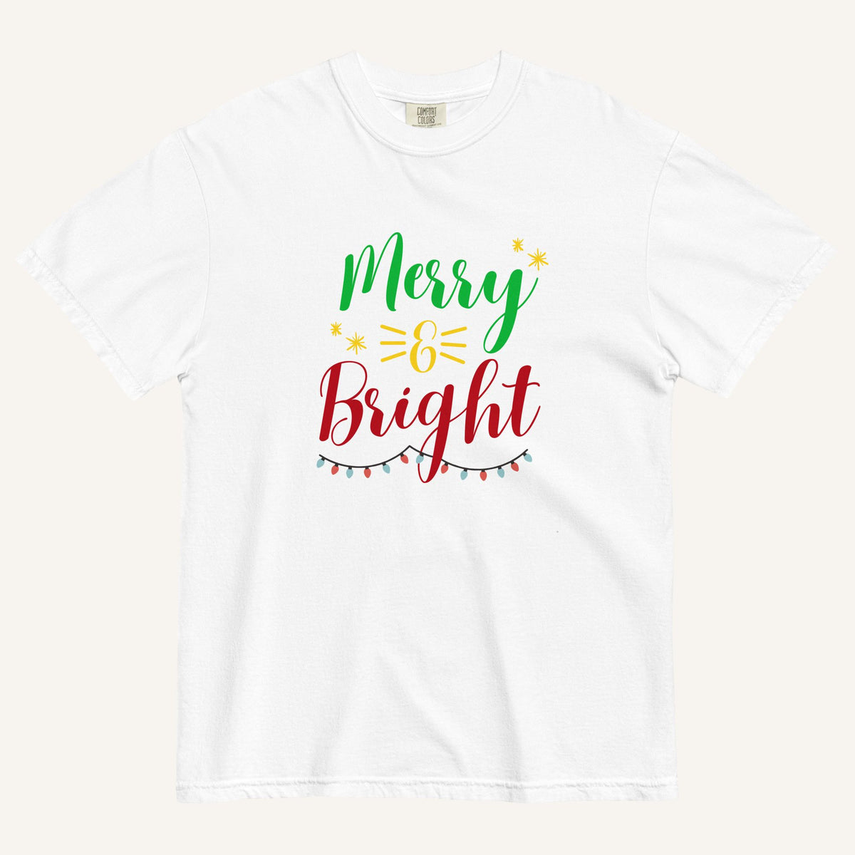 a white t-shirt that has "Merry & Bright" colored text with Christmas lights and star graphics