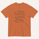 A burnt orange short-sleeve t-shirt with a black graphic print on the front showing fish and loaves of bread, with the text 'He Provides' and 'Matthew 14:13-21'.