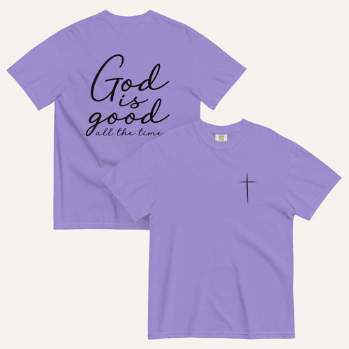 A purple short-sleeve t-shirt shown from both the front and back on a light cream background. The back features the phrase 'God is good all the time' in black script, and the front has a small black cross on the left chest.