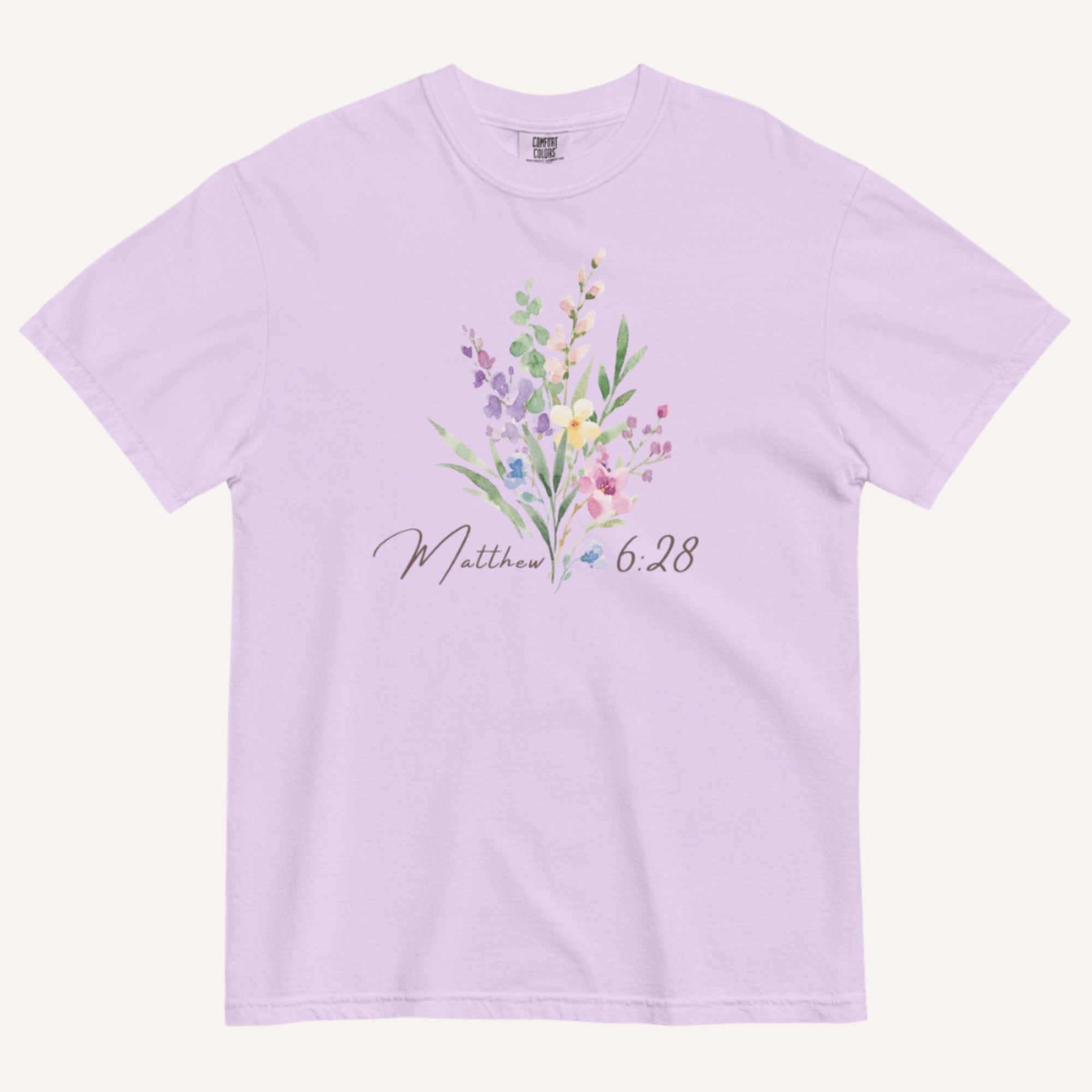 Lavender t-shirt with floral design and 'Matthew 6:28' text on a white background