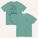 A seafoam green t-shirt shown from both the front and back. The front features a small black cross on the top left. The back features the black text 'There is HOPE in Jesus' in a mix of script and block lettering.