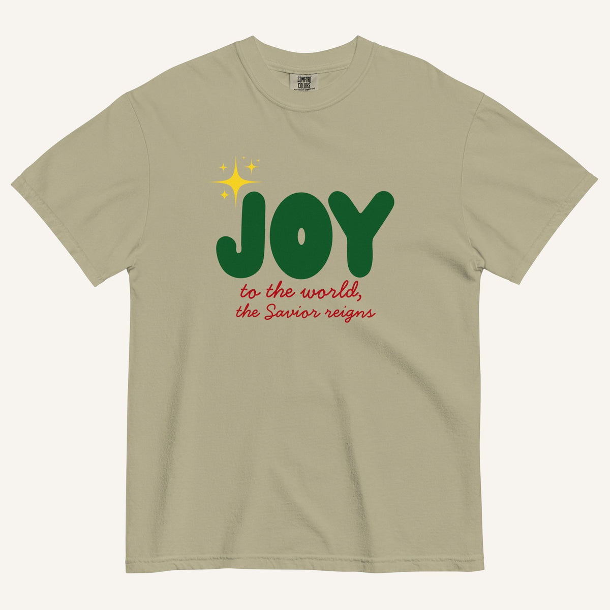 a khaki color t-shirt with the words "Joy to the world, the Savior reigns" in bold colorful font with a star graphic