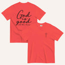 A paprika red short-sleeve t-shirt shown from both the front and back on a light cream background. The back features the phrase 'God is good all the time' in black script, and the front has a small black cross on the left chest.