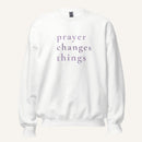 white sweatshirt with 'Prayer Changes Things' purple text on a cream background