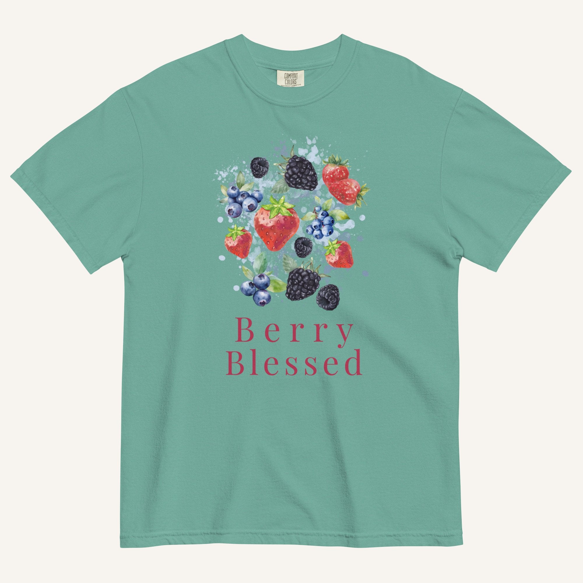 A mint green short-sleeve t-shirt with a colorful graphic of various berries (strawberries, blueberries, blackberries) and the text 'Berry Blessed' printed below it, displayed on a light cream background.