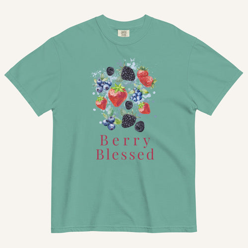 A mint green short-sleeve t-shirt with a colorful graphic of various berries (strawberries, blueberries, blackberries) and the text 'Berry Blessed' printed below it, displayed on a light cream background.