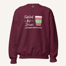 Maroon unisex crewneck sweatshirt featuring a Christmas design with the phrase “Fueled by Jesus …and peppermint mochas,” peppermint illustrations, and a festive red and green peppermint mocha cup graphic.