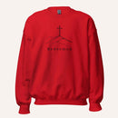 A bright red crewneck sweatshirt featuring a black graphic of a cross on a hill with the word 'Redeemed' printed below it, displayed on a clean off-white background.