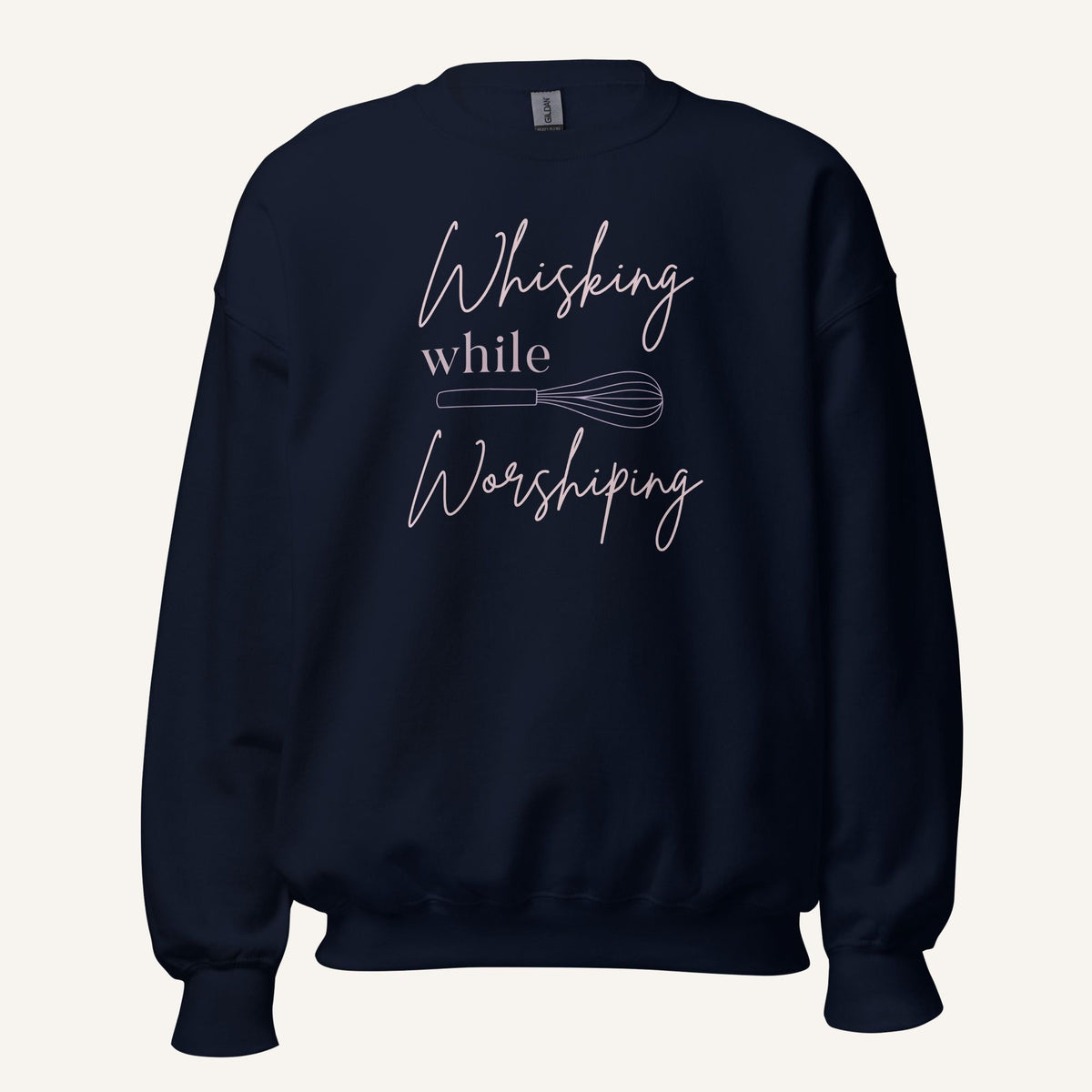 Navy crewneck sweatshirt with "Whisking while Worshiping" pink text with a pink whisk graphic.