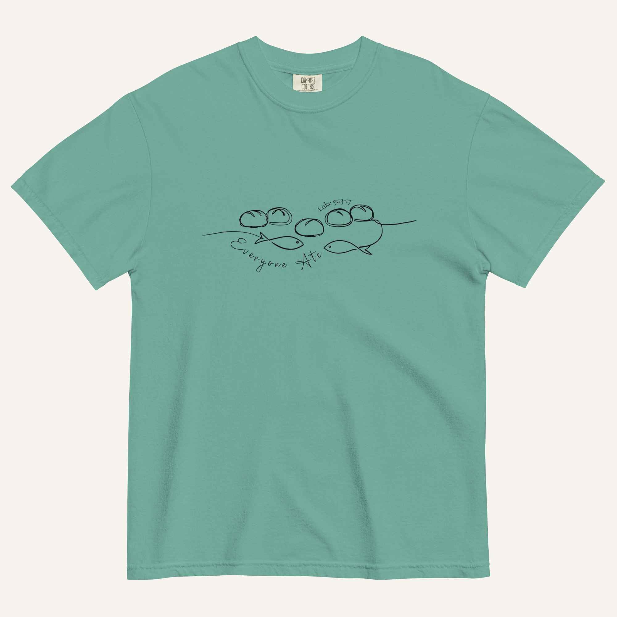 A teal blue short-sleeve crewneck t-shirt with a black graphic of two fish and 5 loaves of bread on a line and the cursive text 'Everyone Ate' across the chest, displayed flat against a light beige background.