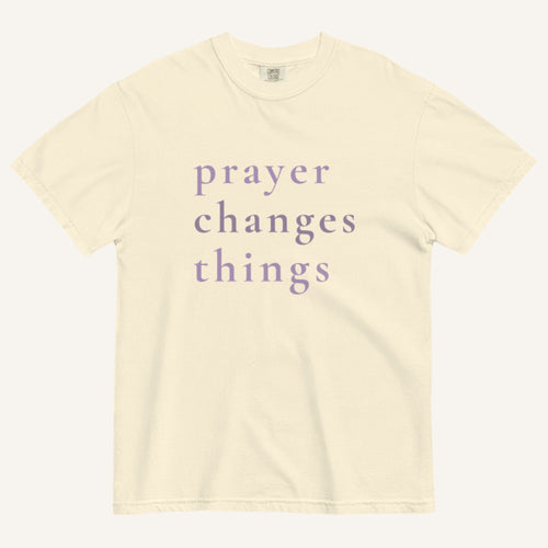 Beige t-shirt with 'prayer changes things' text on a white background