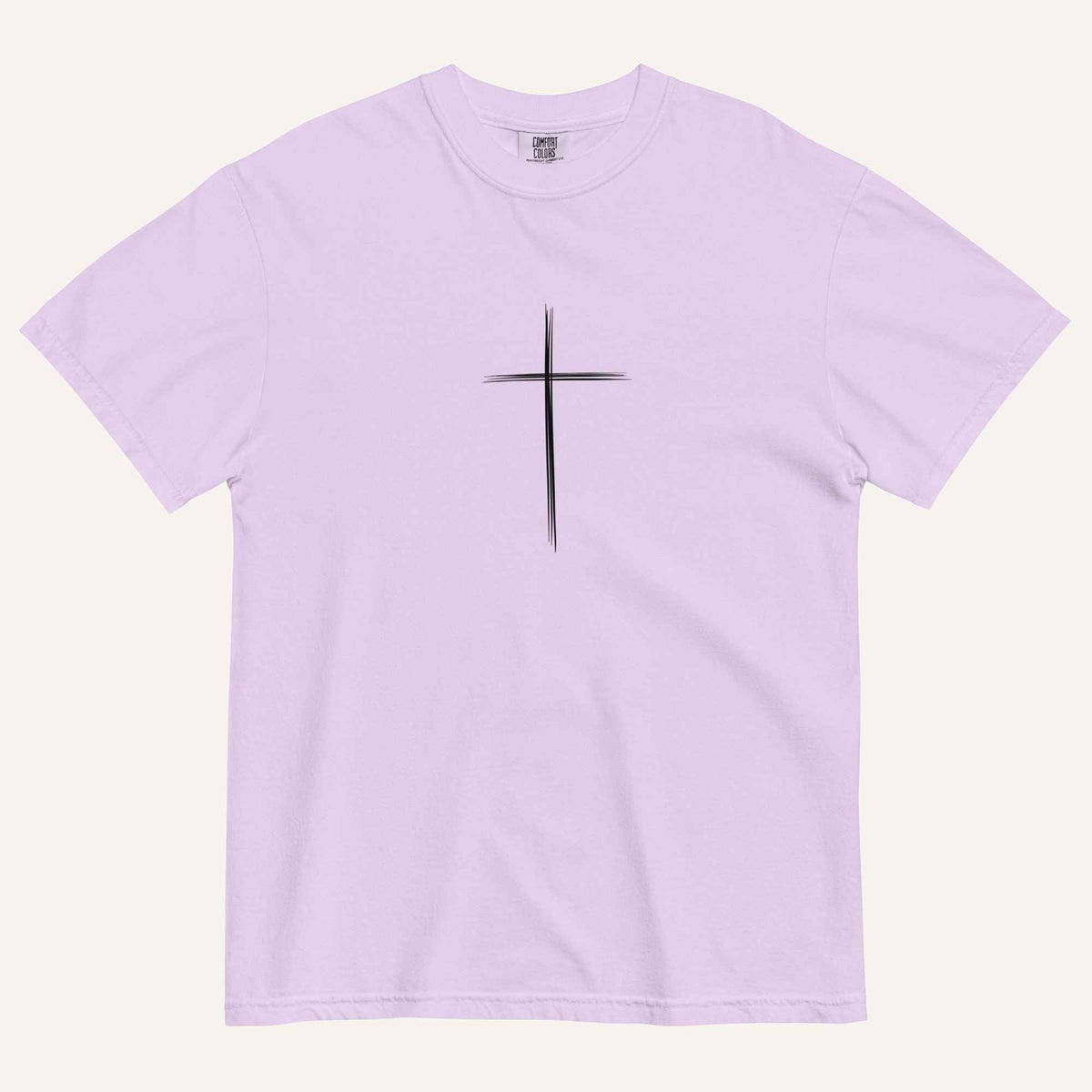 A short-sleeve crewneck t-shirt in a light lavender color, featuring a simple black Christian cross printed on the center chest. The t-shirt is laid flat against a solid, warm off-white background.