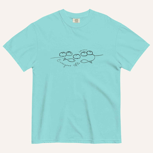 A light aqua blue short-sleeve crewneck t-shirt with a black graphic of two fish and 5 loaves of bread on a line and the cursive text 'Everyone Ate' across the chest, displayed flat against a light beige background.