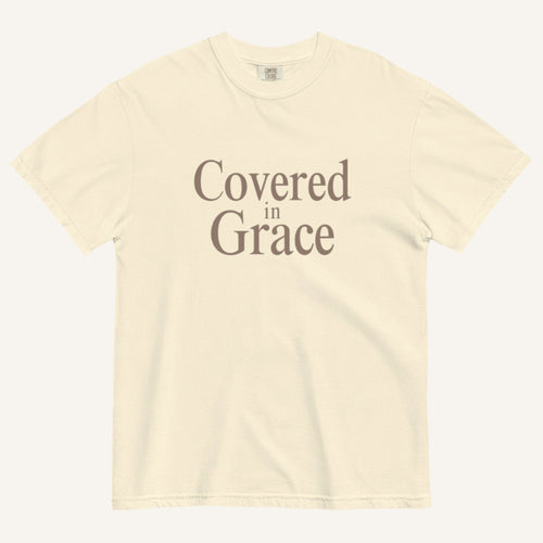 Beige t-shirt with 'Covered in Grace' text on a white background