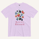A light lavender crewneck t-shirt featuring a watercolor-style graphic of various berries (strawberries, blueberries, blackberries) with the text 'Berry Blessed' printed below in a dusty rose font, displayed on a clean off-white background.