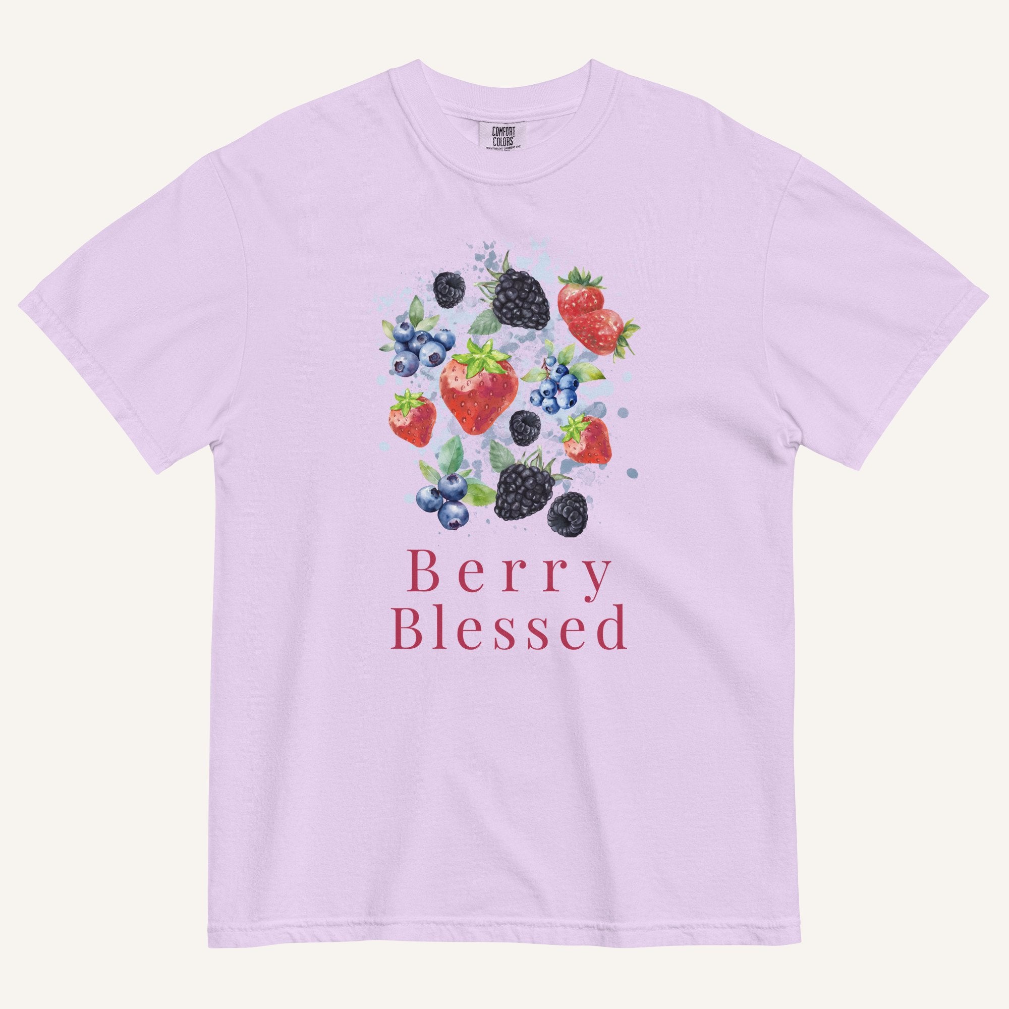 A light lavender crewneck t-shirt featuring a watercolor-style graphic of various berries (strawberries, blueberries, blackberries) with the text 'Berry Blessed' printed below in a dusty rose font, displayed on a clean off-white background.