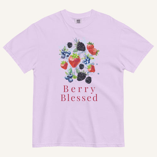 A light lavender crewneck t-shirt featuring a watercolor-style graphic of various berries (strawberries, blueberries, blackberries) with the text 'Berry Blessed' printed below in a dusty rose font, displayed on a clean off-white background.