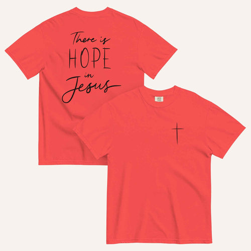A reddish pink t-shirt shown from both the front and back. The front features a small black cross on the top left. The back features the black text 'There is HOPE in Jesus' in a mix of script and block lettering.