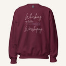 Maroon crewneck sweatshirt with "Whisking while Worshiping" pink text with a pink whisk graphic.
