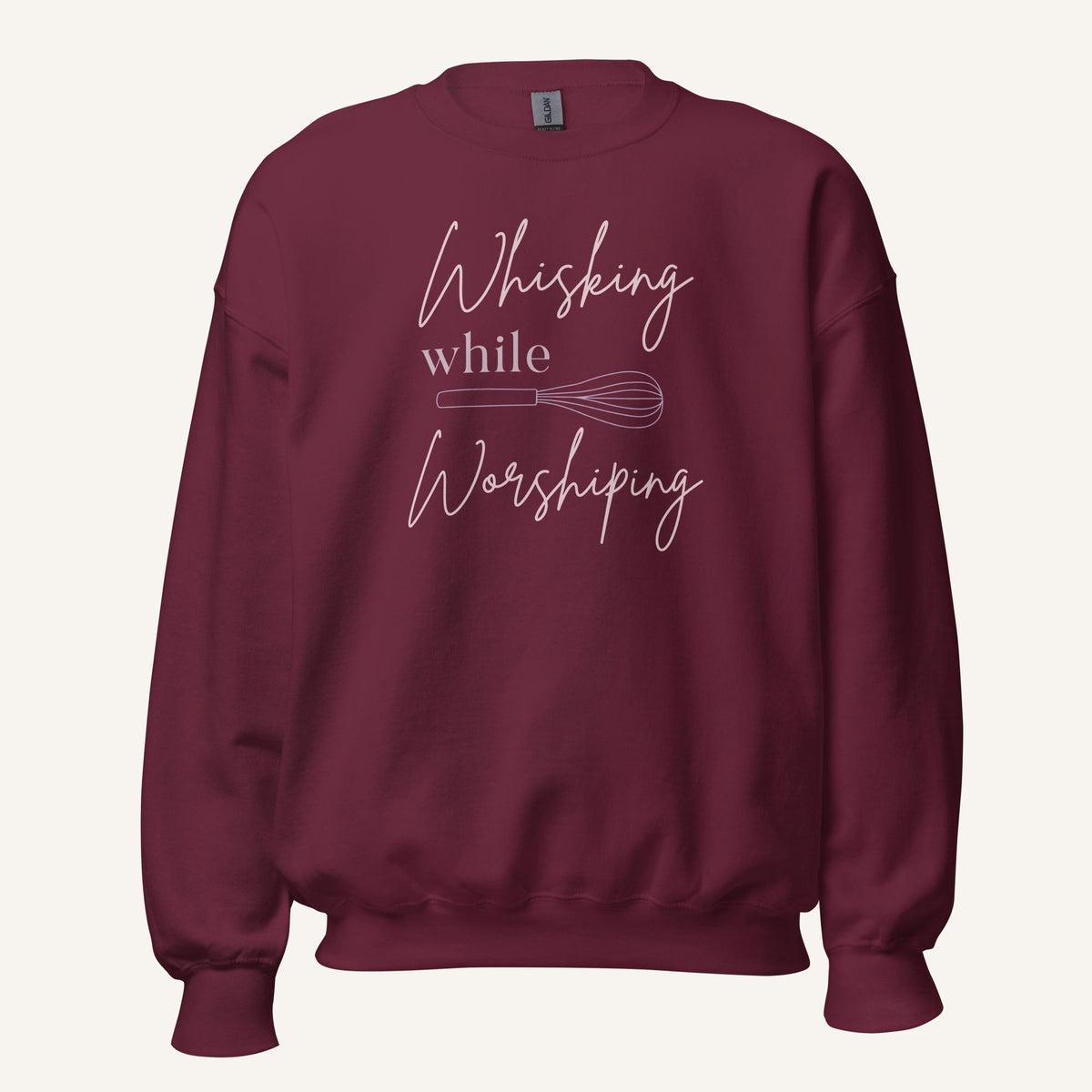 Maroon crewneck sweatshirt with "Whisking while Worshiping" pink text with a pink whisk graphic.