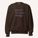 brown sweatshirt with 'Prayer Changes Things' purple text on a cream background