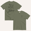 An army green t-shirt shown from both the front and back. The front features a small black cross on the top left. The back features the black text 'There is HOPE in Jesus' in a mix of script and block lettering.