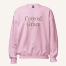 light pink sweatshirt with 'Covered in Grace' text on a cream background