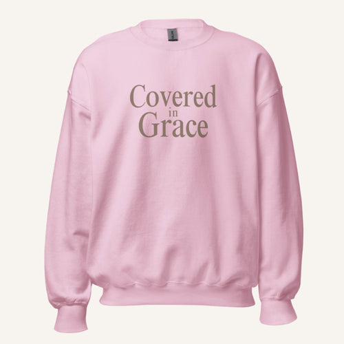 light pink sweatshirt with 'Covered in Grace' text on a cream background