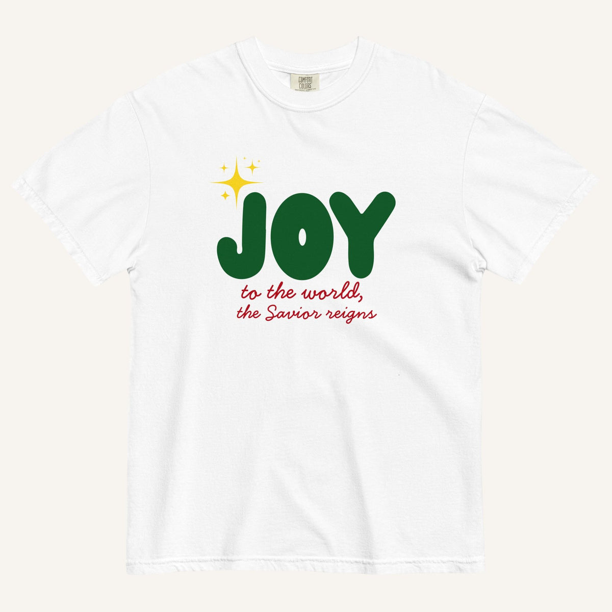 a white t-shirt with the words "Joy to the world, the Savior reigns" in bold colorful font with a star graphic