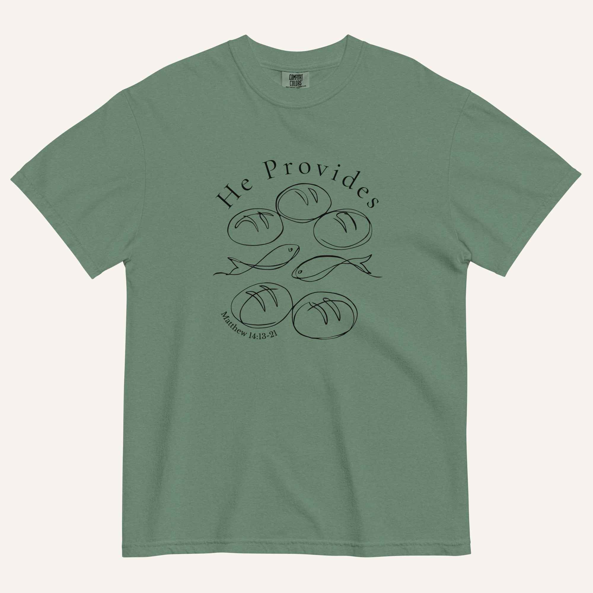 A sage green short-sleeve t-shirt with a black graphic print on the front showing fish and loaves of bread, with the text 'He Provides' and 'Matthew 14:13-21'.