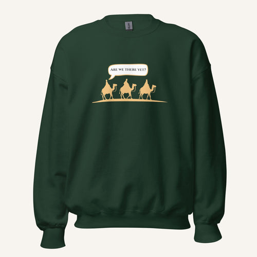 Dark green unisex crewneck sweatshirt featuring a gold desert scene with three camels and a speech bubble reading “Are we there yet?”