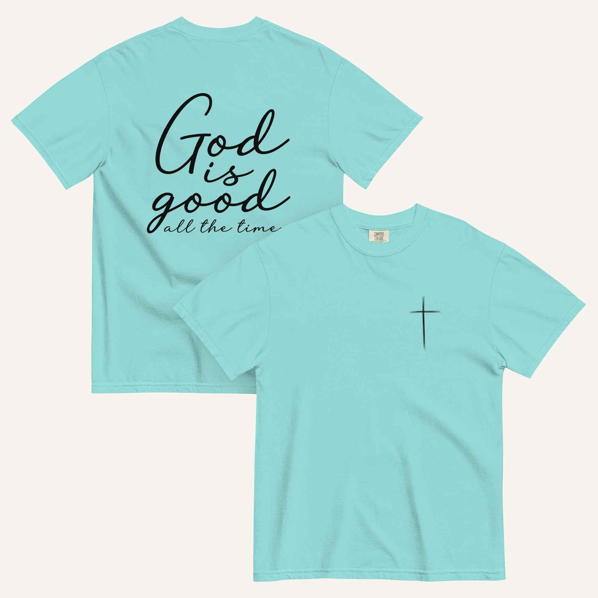 A lagoon blue short-sleeve t-shirt shown from both the front and back on a light cream background. The back features the phrase 'God is good all the time' in black script, and the front has a small black cross on the left chest.