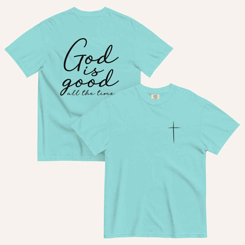 A lagoon blue short-sleeve t-shirt shown from both the front and back on a light cream background. The back features the phrase 'God is good all the time' in black script, and the front has a small black cross on the left chest.
