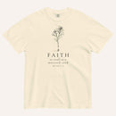 An ivory short-sleeve crewneck t-shirt with a black line-art mustard seed graphic and the text 'FAITH as small as a mustard seed' and 'MATTHEW 17:20' printed on the front, displayed against a light cream background.