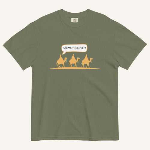 a green t-shirt with 3 men riding camels in the color yellow with a chat bubble with the text "are we there yet?"