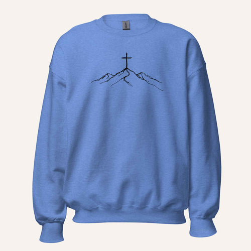 A blue crewneck sweatshirt featuring a black line art graphic of a cross on top of simple mountains on the chest, displayed against a solid off-white background.