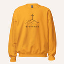 A yellow orange crewneck sweatshirt featuring a black graphic of a cross on a hill with the word 'Redeemed' printed below it, displayed on a clean off-white background.