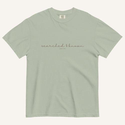 Light green t-shirt with 'Searched & Known' text on a cream background